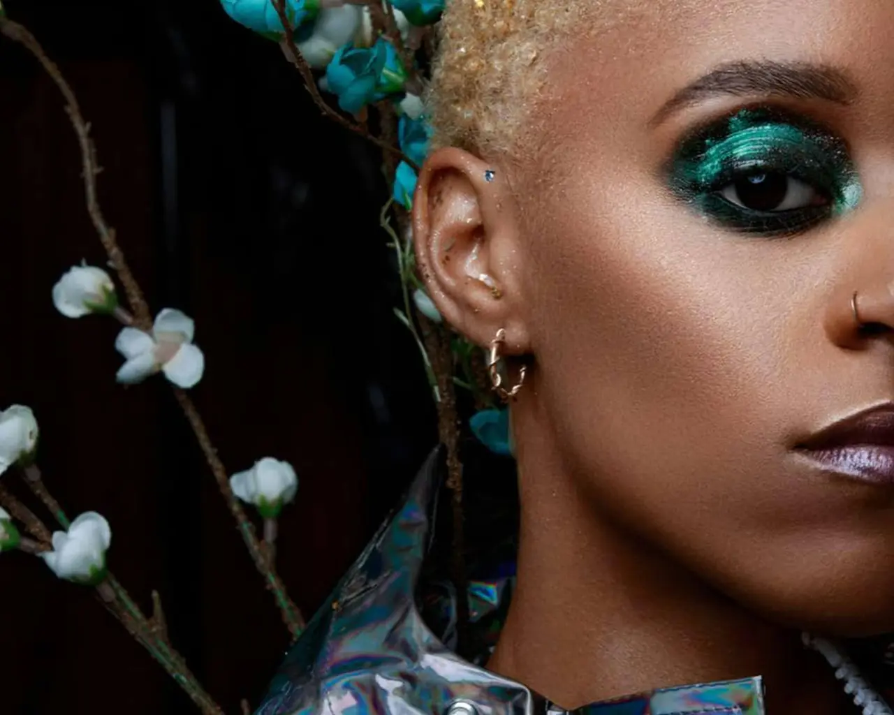 A woman with green eye make-up looking at the camera