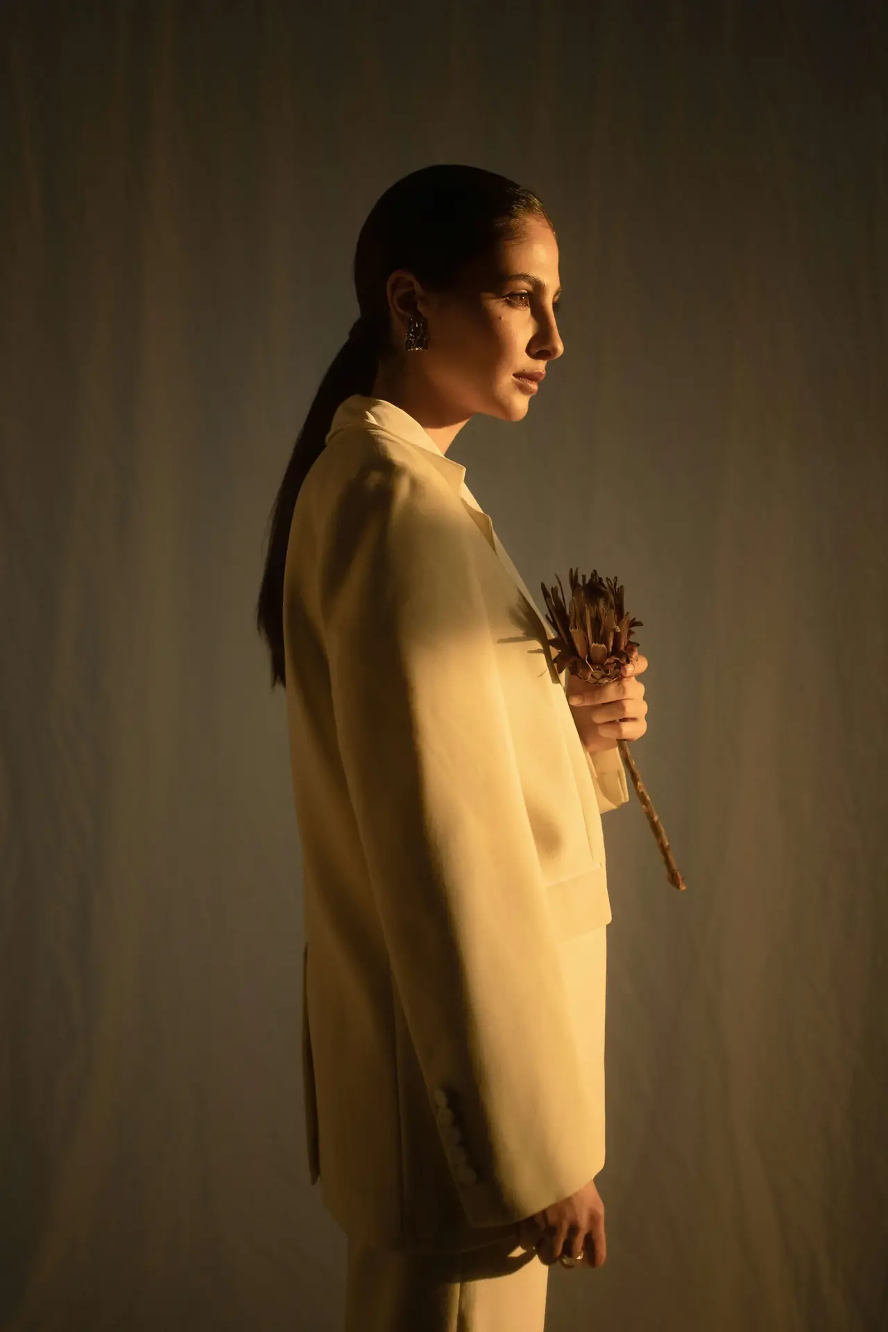 A woman in an off-white suit holding flowers