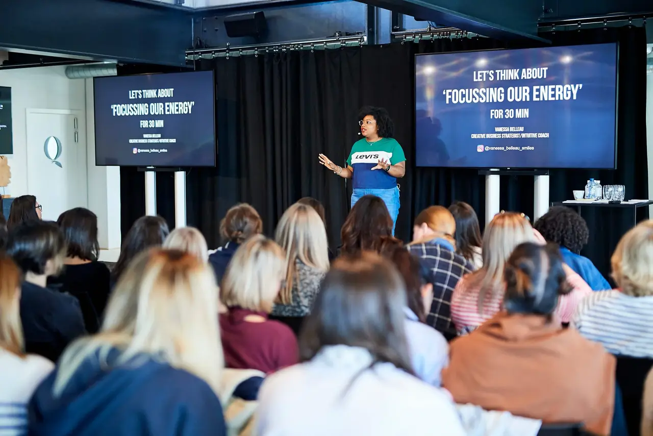 Vanessa speaking to a seminar audience in front of a presentation screen